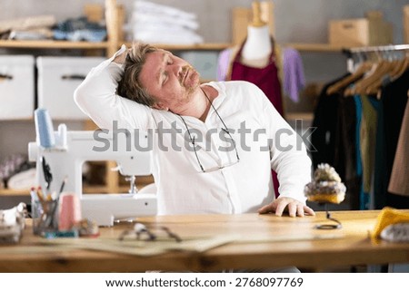 Sitting at workplace, man tailor does limbering