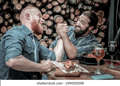 Situation is heating up. Portrait of two friends fighting in an all-out arm-wrestling battle after drinking a couple of beer glasses. - Powered by Shutterstock