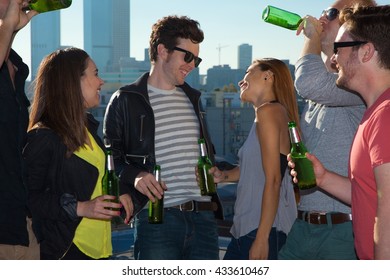 Six Adult Friends Flirting And Drinking Beer At Rooftop Bar With Los Angeles Skyline, USA