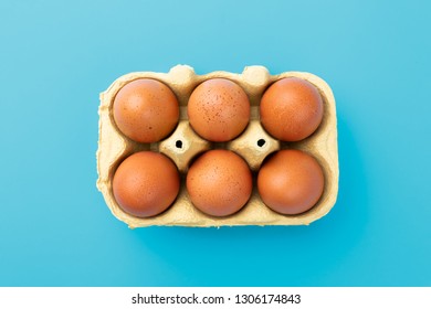 Six Brwon Eggs In Mould Box On Blue Turquoise Background, View From Above