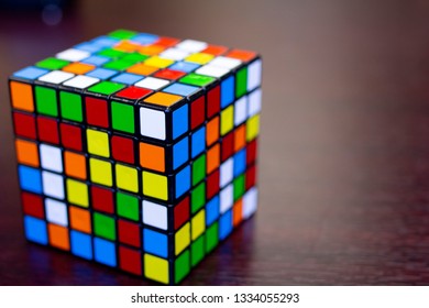 A six by six puzzle cube mixed up sitting on a wood table