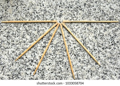 Six Chopsticks Create A Fan-shape On A Granite Counter Overhead View.