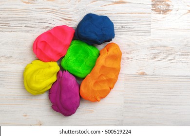 Six Colorful Lumps Of Crumpled Plasticine Put Together On A Wood Surface. Kids Activities. DIY Ideas. Playing With Modeling Clay.