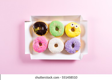 Six colorful round donuts in the box. Flat lay, top view.