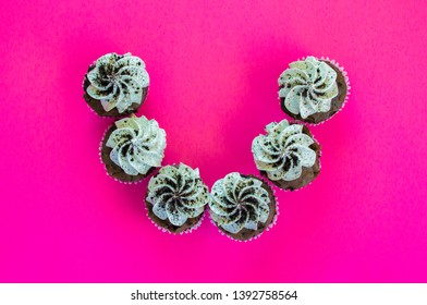 Six Cookies And Cream Cupcakes Arranged In A Semi Circle On A Hot Pink Background Viewed From Above