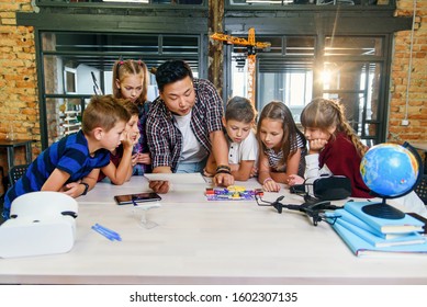 Six Creative School Children With Young Asian Teacher Study An Electronic Constructor With Fan And Turn On Flashlight. Creative Pupils With Teacher Working On The Tech Project At School.