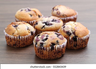 Six delicious home-made blueberry muffins on a wooden background