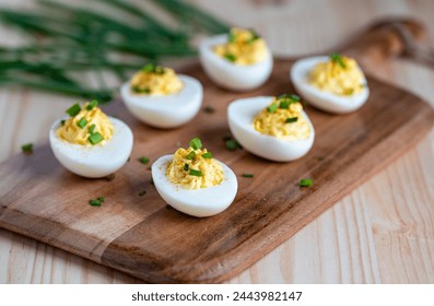 Six deviled eggs on a cutting board garnished with chopped chives - Powered by Shutterstock