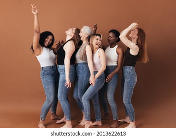 Six diverse women laughing together. Females with different body types having fun while standing against a brown background.