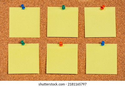 Six empty yellow sticky notes on a cork board with drawing pins, copy past