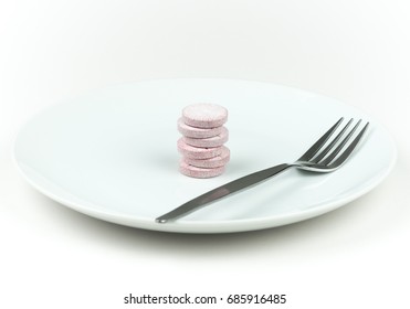 Six Food Supplement Tablets And Fork On A White Plate