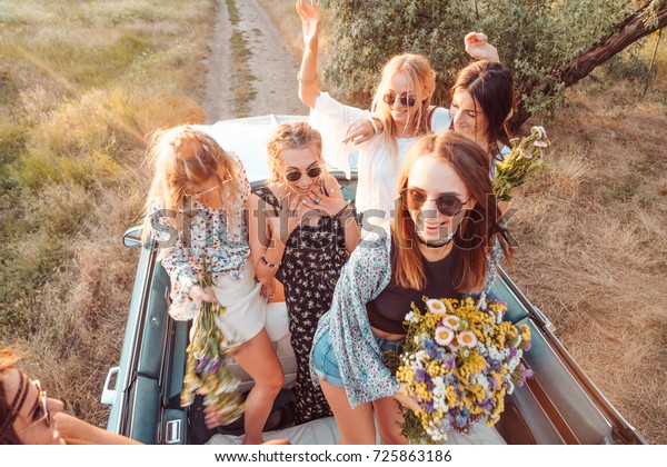 Six girls\
have fun on the car in the\
countryside