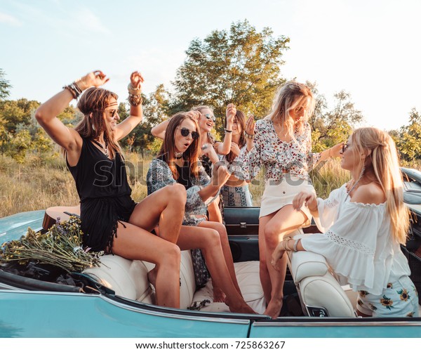 Six girls\
have fun on the car in the\
countryside