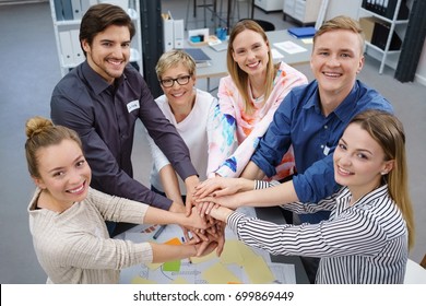 Six Happy, Smiling Work Colleagues Participating In A Hands In Team Building Exercise In An Office Room.