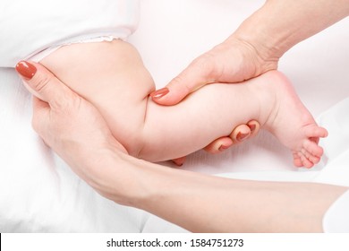 Six Month Baby Girl Receiving Osteopathic Or Chiropractic Treatment In Pediatric Clinic. Manual Therapist Manipulates Chils's Knee