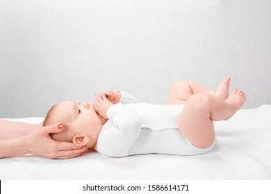 Six month baby girl receiving osteopathic or chiropractic treatment in pediatric clinic. Manual therapist manipulates child's head and neck - Powered by Shutterstock