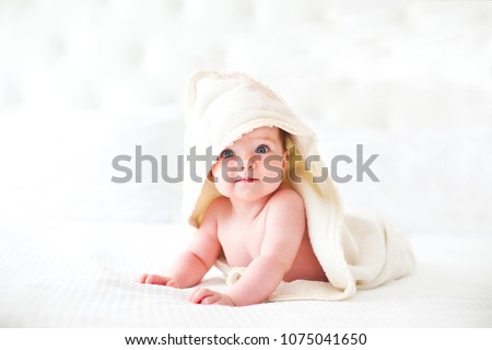 Six month baby wearing towel after bath. Childhood and baby care concept