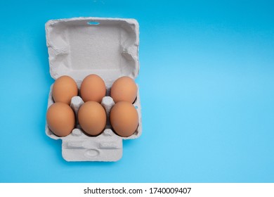 Six Pack Of Eggs In Carton On Blue Background - Top View With Copy Space