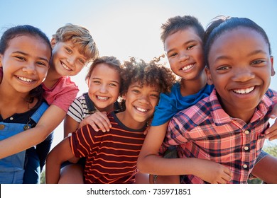 Six pre-teen friends piggybacking in a park, close up portrait - Shutterstock ID 735971851