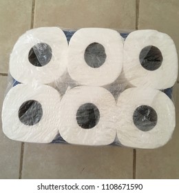 Six Rolls of Toilet Paper New in Wrapper Packaged on Tile Floor