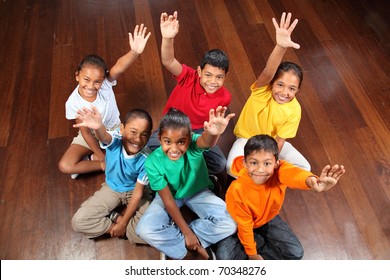 Six school children sitting in classroom hands up