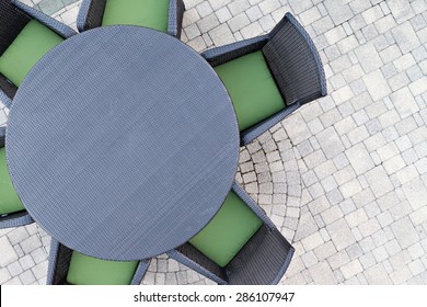 Six Seater Outdoor Patio Set With Comfortable Green Cushions And A Round Dining Table On A Brick Paved Open-air Patio With Copy Space, Overhead View