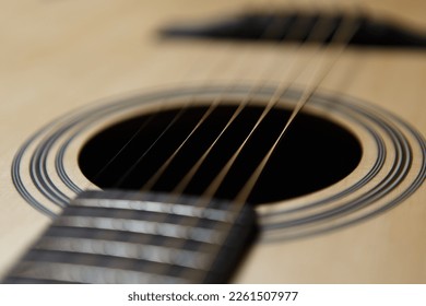 Six string acoustic guitar in close up. Focus on metal strings and hole in sound board