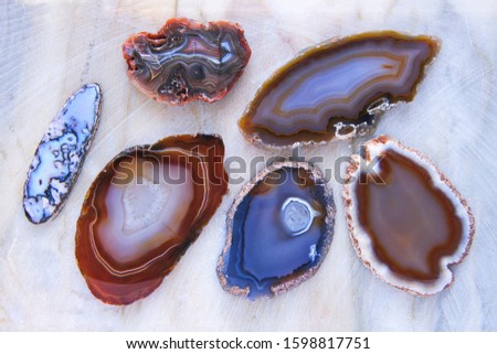 Six translucent samples of agate mineral stones on marble plate close-up. Macro shooting of specimens of natural mineral agate crystal of various colors as a background.
