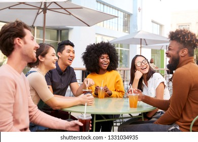 Six Trendy Millennial Friends Sit Drinking Cold Brews Talking And Laughing Outside A Cafe