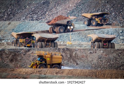 Six trucks in a busy modern gold mine in Western Australia. One water truck and five large haul truck transport gold ore from the Super Pit, Opencast mine. All logos removed
