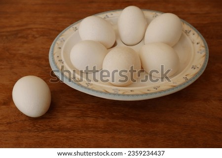 six white Chicken eggs in a Boiled Eggs Serving Plate with one egg outside, top view on Brown wood Table. For Happy Easter, copy space. Breakfast with soft-boiled egg served on a white wooden table.