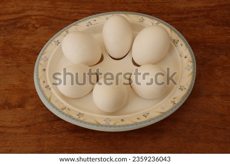 six white Chicken eggs in a Boiled Eggs Serving Plate, top view flat layer on Brown wood Table. Breakfast with soft-boiled egg served on a wooden table. Chicken eggs on a plate.