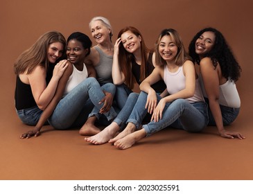 Six Women Of Different Ages Sitting Together In Studio On Brown Background. Multi-ethnic Group Of Diverse Females Having Good Times.