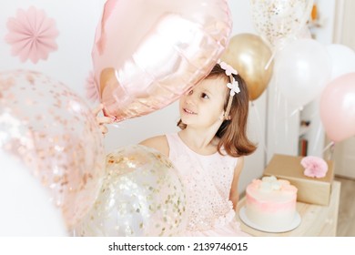 Six Year Girl Wearing Dress Holding Light Pink Heart Shaped Balloon. Home Birthday Party