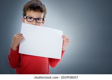 Six Year Old Caucasian Boy In Studio With Blank A4 Sheet Of Paper In Hands. 