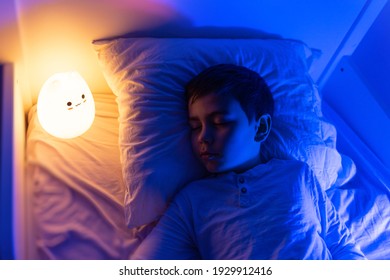 Six Years Old Bouy Sleep With LED Night Lamp, School Child Dreaming. Kid Angry Of Darkness.