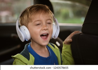 Six Years Old Boy With Headphones Singing In The Car.