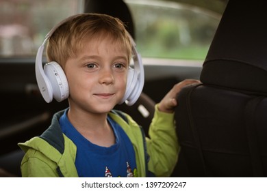 Six Years Old Boy With Headphones Singing In The Car.