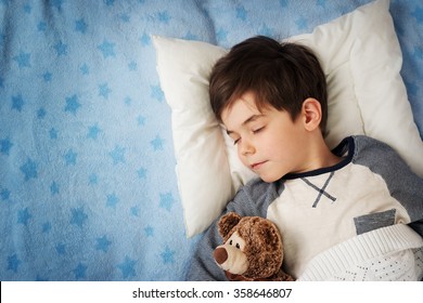 six years old child sleeping in bed with alarm clock - Powered by Shutterstock