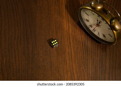six-mesh dice on a wooden table next to an old clock showing almost 12 o'clock