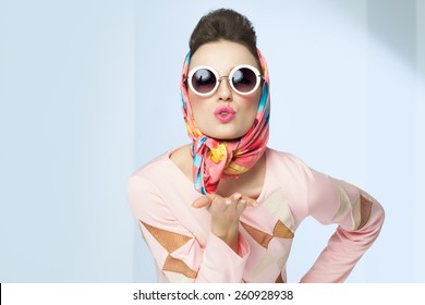 Sixties Style Girl Blowing A Kiss. Retro Fashion With Silk Scarf And Sunglasses.