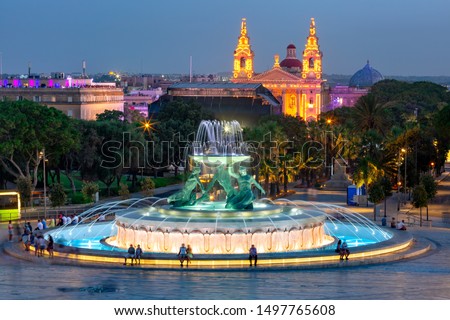 Sizable landmark Triton Fountain, featuring multiple bronze tritons and St. Publius church in Old Town of Valletta, Capital city of Malta