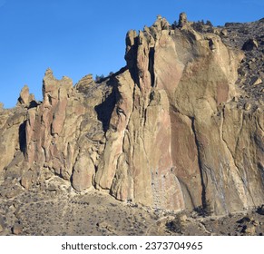 Size perspective is shown in photo of mountain with climbers appearing as small specks on cliff face.