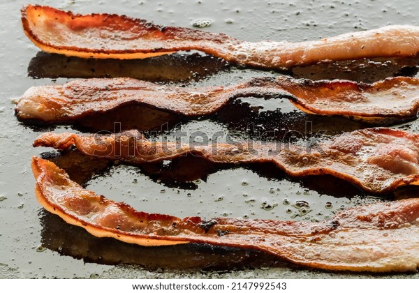 Sizzling bacon frying on a\
griddle pan.