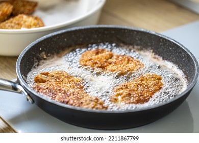 Sizzling Hot Oil With Schnitzel Frying In It In A Dark Pan.