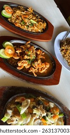 Sizzling Indonesian delights! Enjoy crispy fried prawns, stir-fried noodles, and mixed vegetables, served hot on platters. Savory and satisfying. #IndonesianFood #SizzlingPlate #AsianCuisine #Foodie