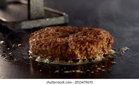 Sizzling Juicy Thick Ground Beef Burger On A Grill In Close Up Centered In A Panorama Banner With Copyspace With Rising Steam And Bubbling Meat Juices