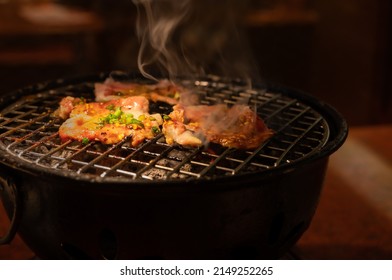 Sizzling pork slices grill on charcoal, Korean or Japanese BBQ style cuisine.