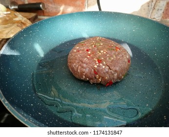 Sizzling Raw Turkey Burger With Seasoning On A Hot Frying Pan 