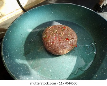 Sizzling Raw Turkey Burger With Seasoning On A Hot Frying Pan 